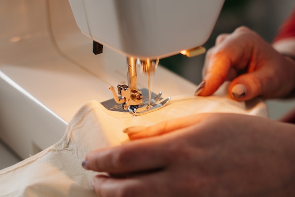 man using white colored sewing machine