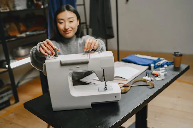 woman using gray colored sewing machine 